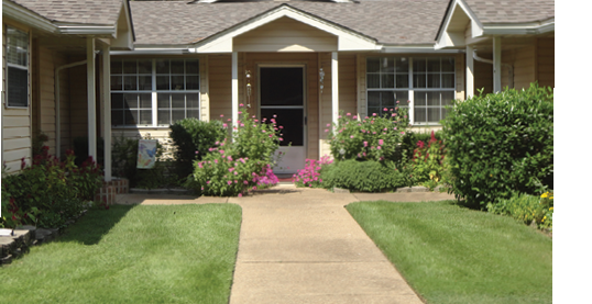 A house with a white door and a walkway leading to it. Description generated by AI