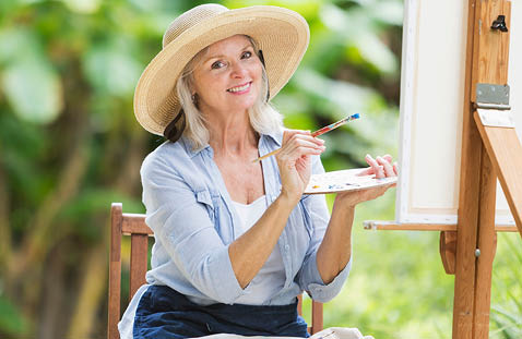 A woman wearing a hat and blue shirt is painting a picture. AI generated content