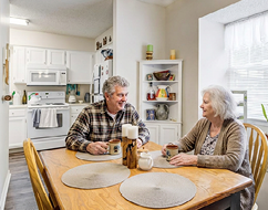 A kitchen with a wooden dining table and chairs. The table is set with plates and a vase. A potted plant is on the window sill. AI generated content